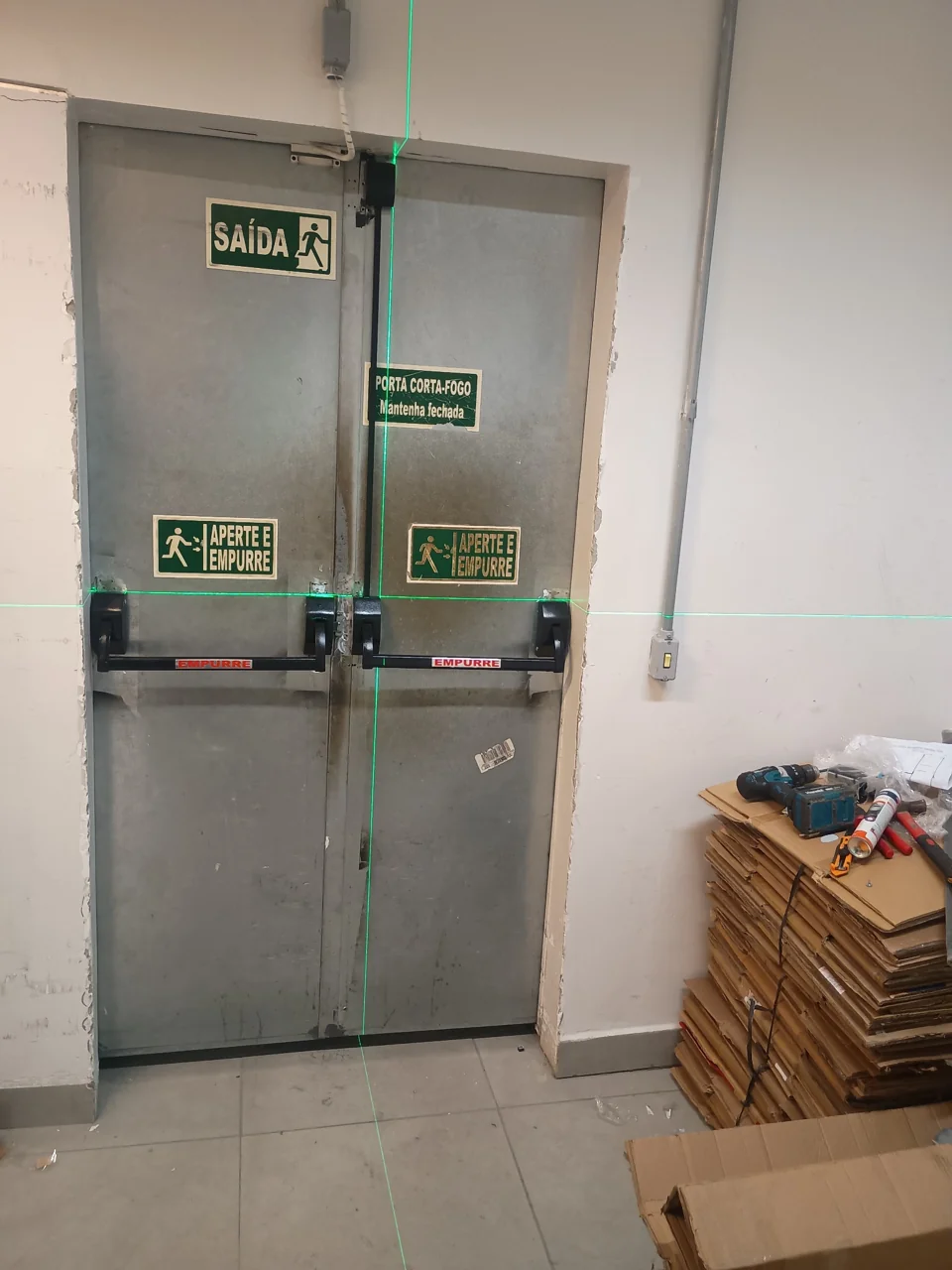 Porta metálica com barras horizontais e sinalização de saída
